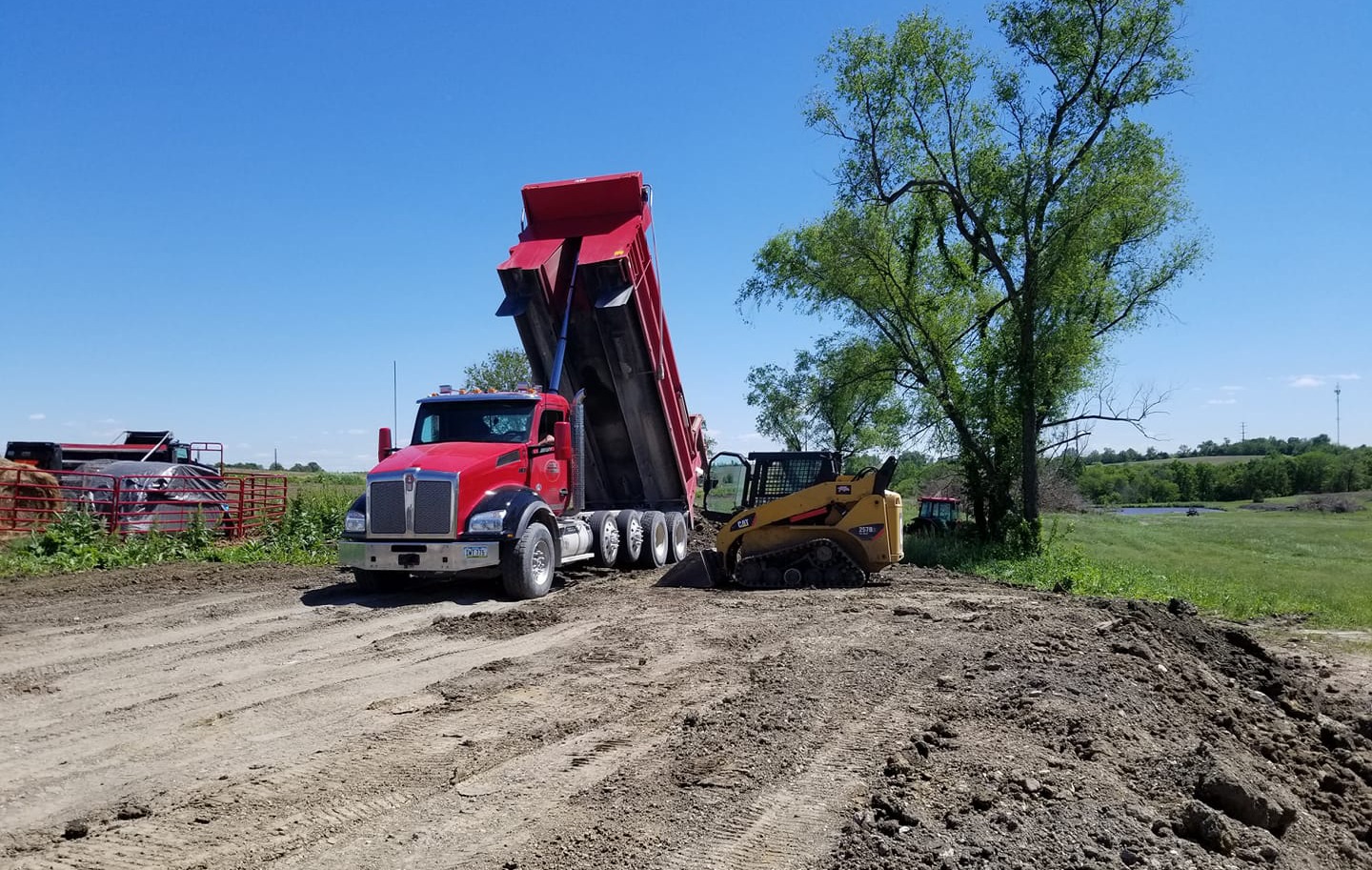 Dump truck and skid loader used on an excavating and grading project.